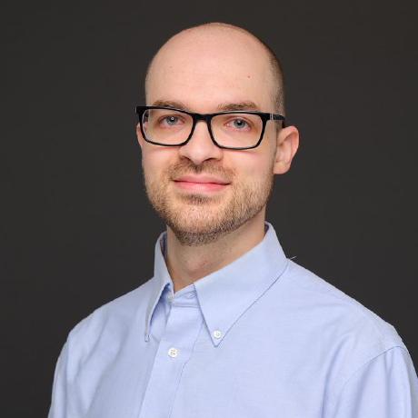 Professional headshot of a white man with a shaved head, short beard, and glasses.