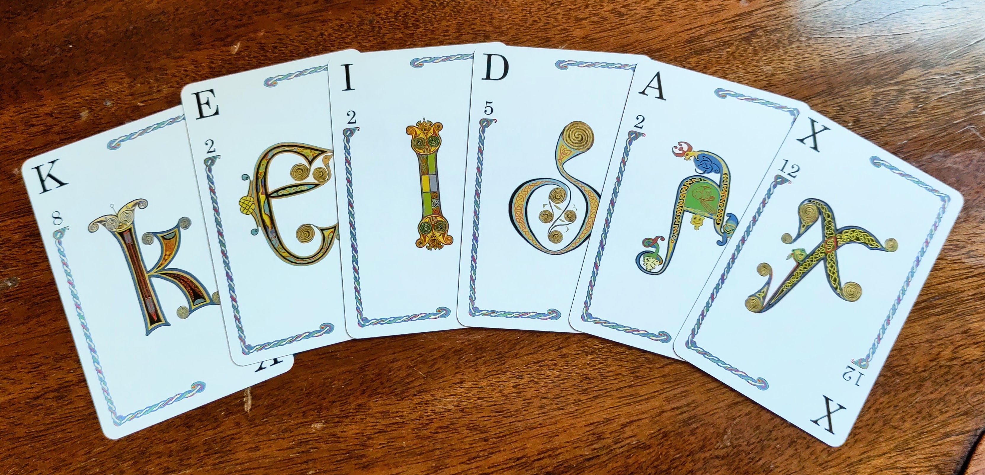 A set of Quiddler cards on a wooden surface that spell KEIDAX